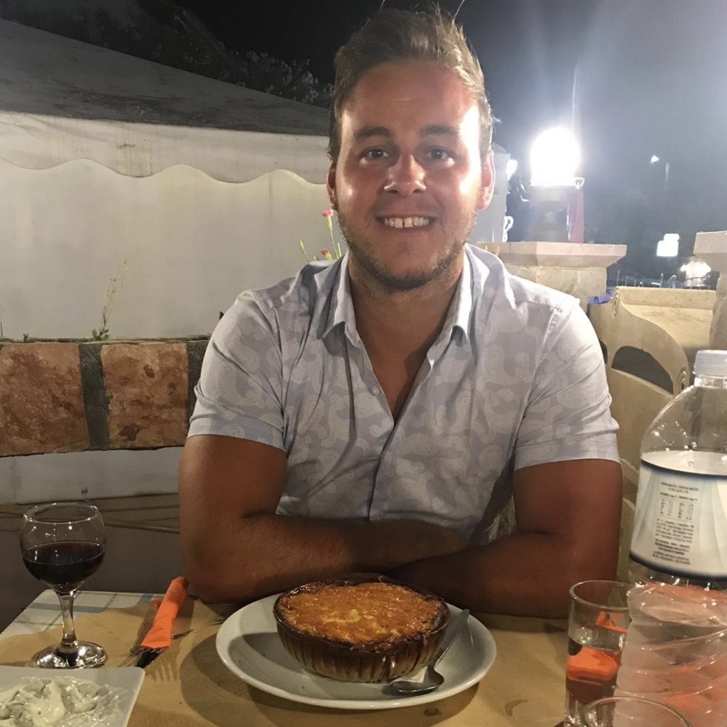 A man with some moussaka at a restaurant.