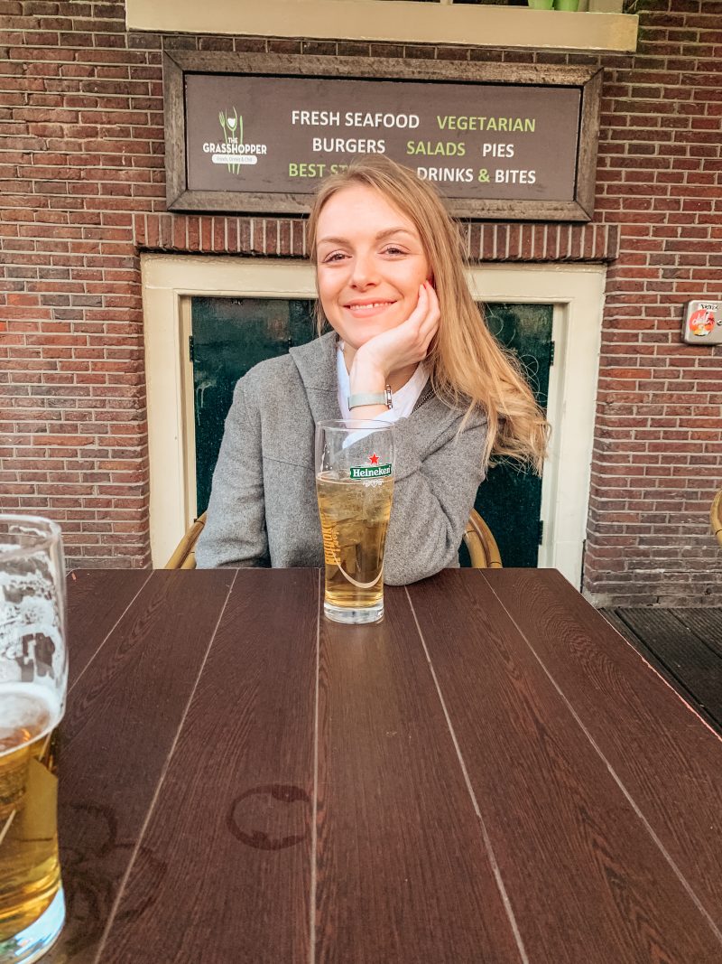 A woman sat at a table with a Heineken beer.