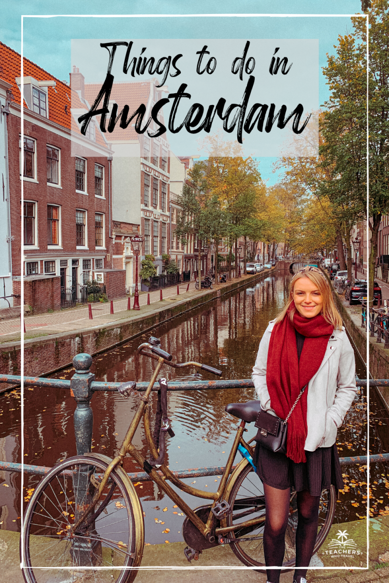 A woman stood on a bridge next to a canal with a bike as part of visiting Amsterdam on a budget.
