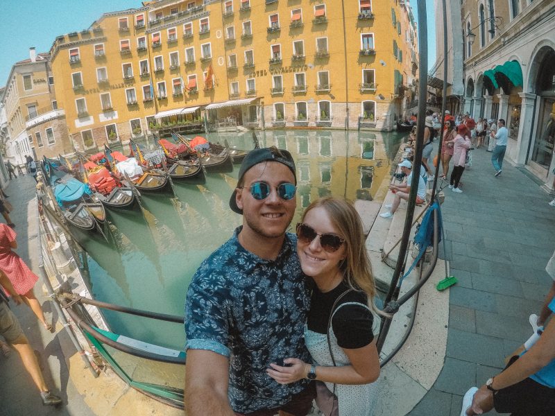 A side street with gondolas with colourful buildings in the background. Things to do in Venice