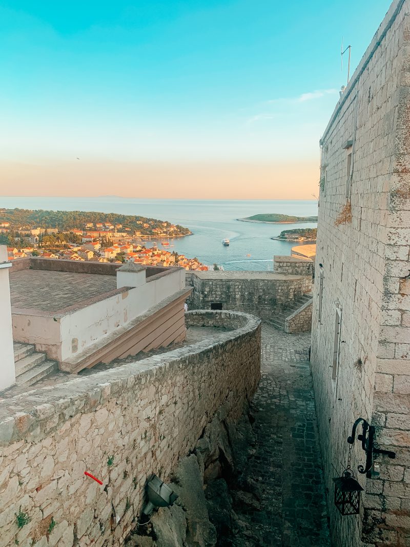 Castle walls with Hvar old town, ocean, boats and islands in the turquoise background. What to do in Hvar