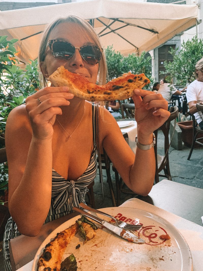 A woman eating pizza with the crust in the shape of a smile. A day in Naples itinerary