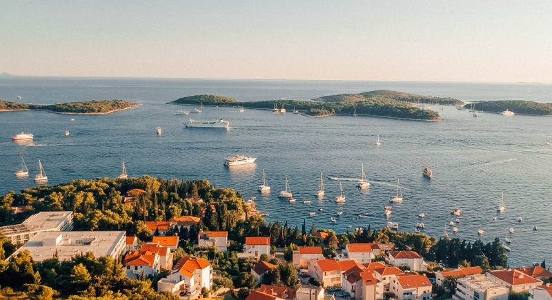 Hvar during sunset with islands and boats in the ocean. Things to do in Hvar