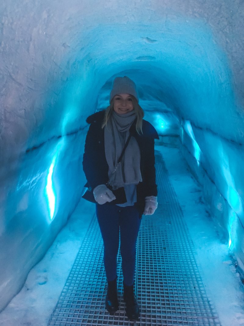 A woman walking through an ice cave tunnel at Perlan in Reykjavik