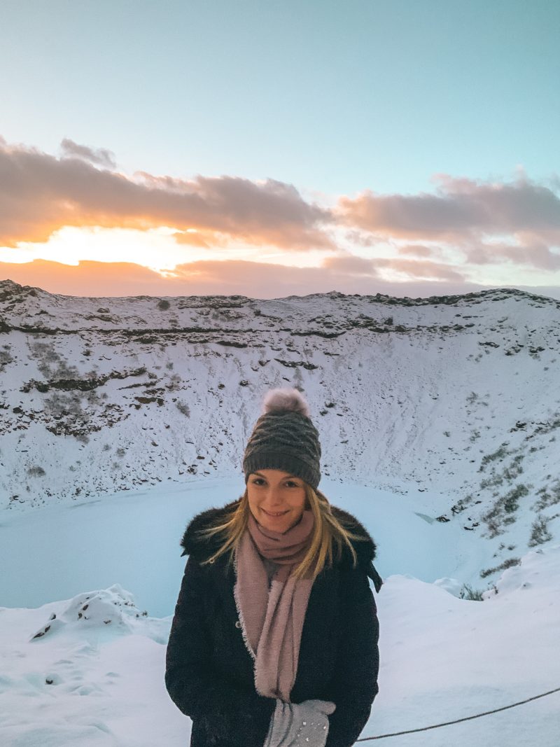 A snowy Kerid crater with a colourful skyline as part of the golden circle tour in Iceland.