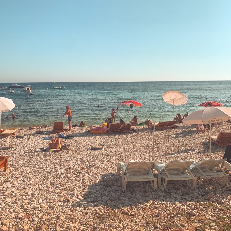 Milna beach with deck chairs and pebbles with turqoise water nearby. Best beaches in Hvar