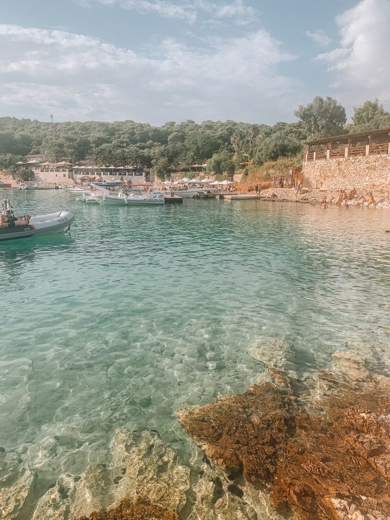 Turquoise water surrounded by rocks and beach front bars. What to do in Hvar