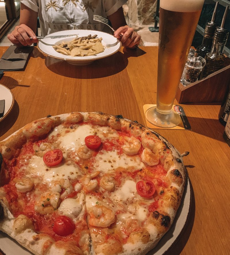 Pizza and pasta with a beer on a table at a restaurant in Hvar