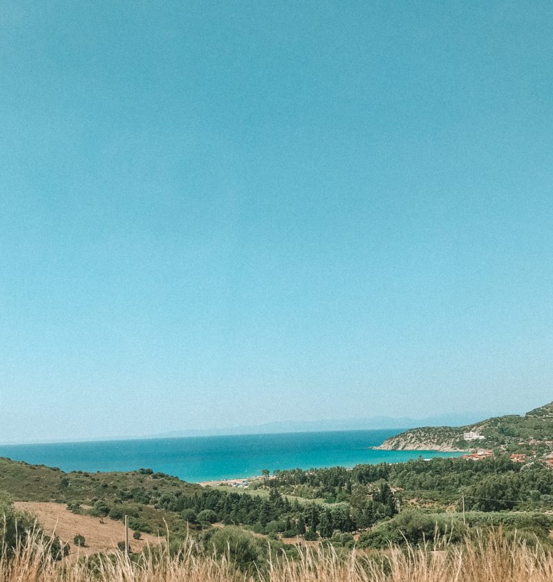 Travelling to the beaches in Sardinia. Ocean and green grass and bushes nearby.