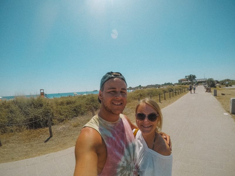 A couple taking a selfie on the road near a beach in Sardinia
