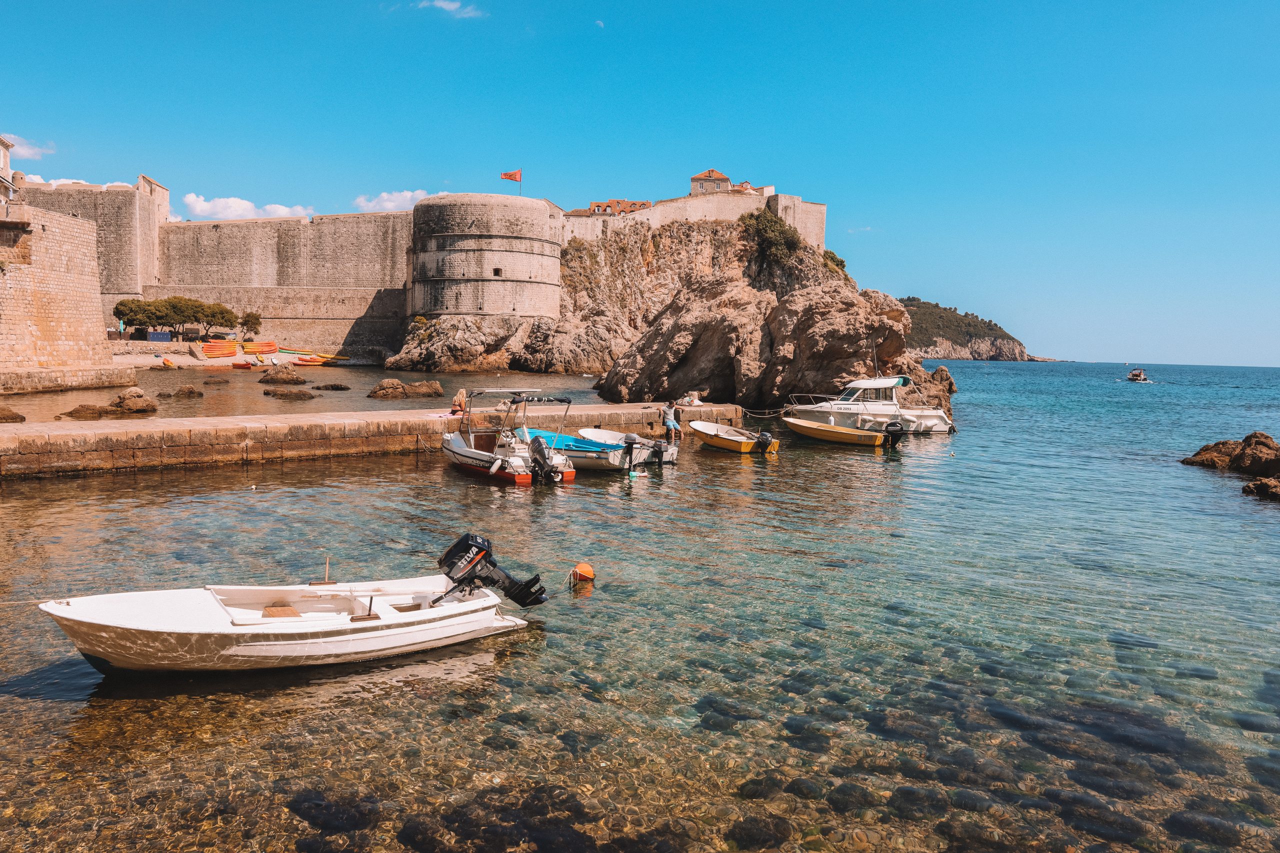 Boats in the ocean and a castle in the background. What to do in Dubrovnik.