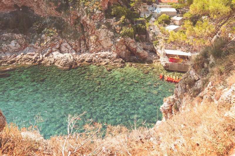 Turquoise ocean with orange and yellow kayaks in them. Things to do in Dubrovnik