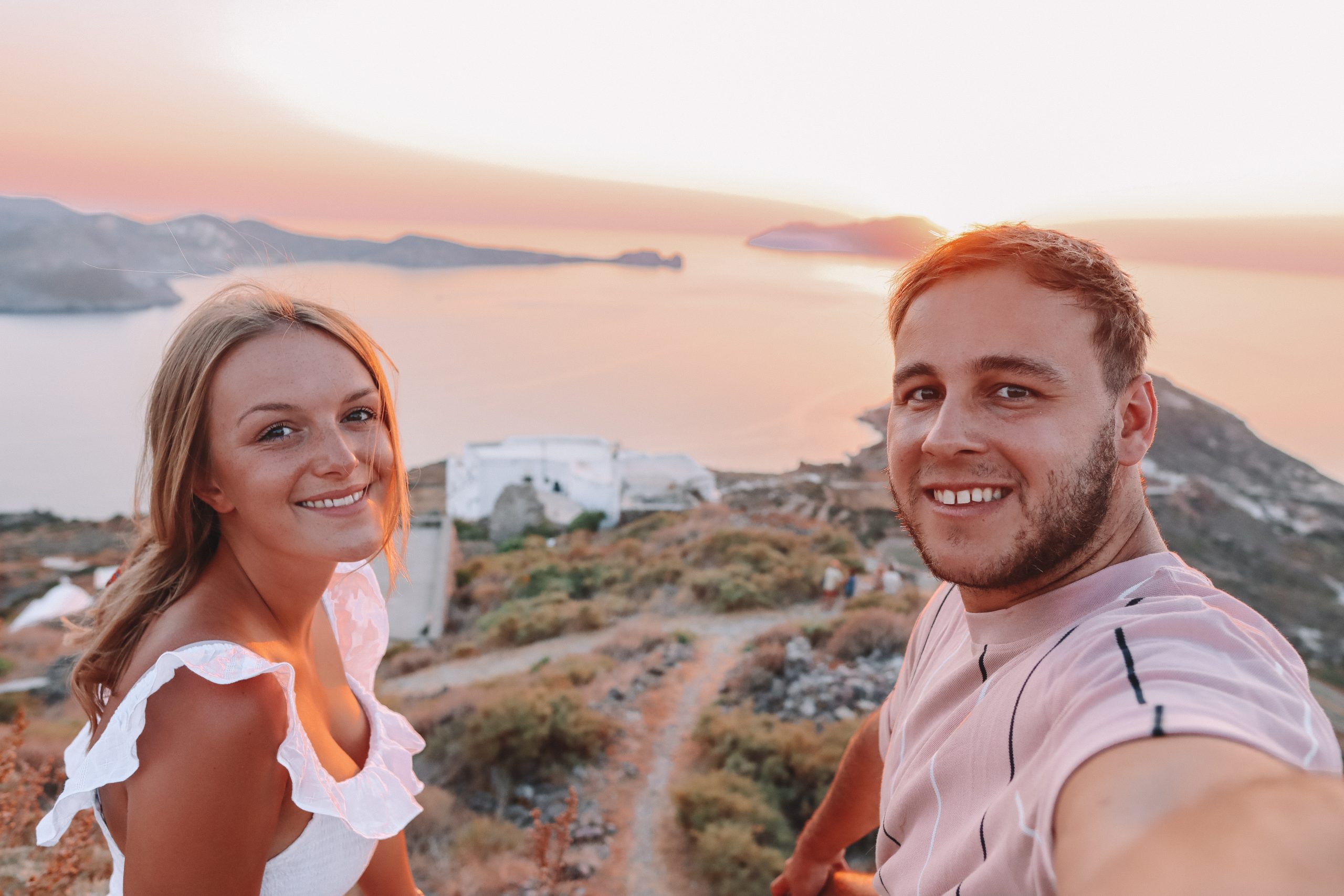 A couple taking a selfie with the ocean and islands in the background
