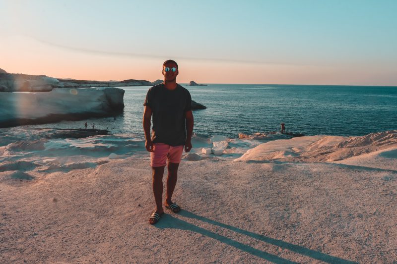 A man stood in front of the Sarakiniko rocks during sunset