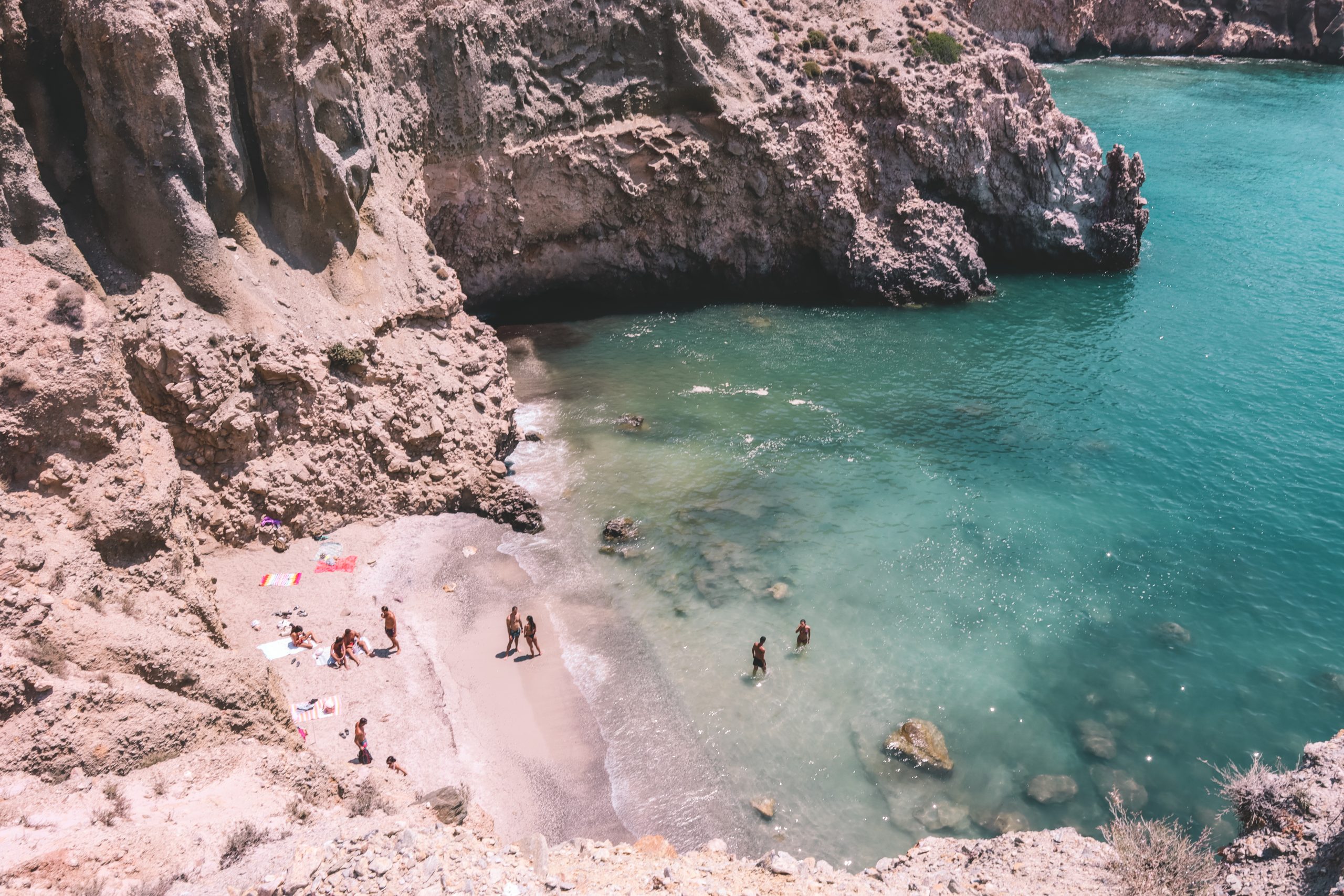 Tsigrado beach with people bathing and the turquoise sea nearby. Best beaches in Milos