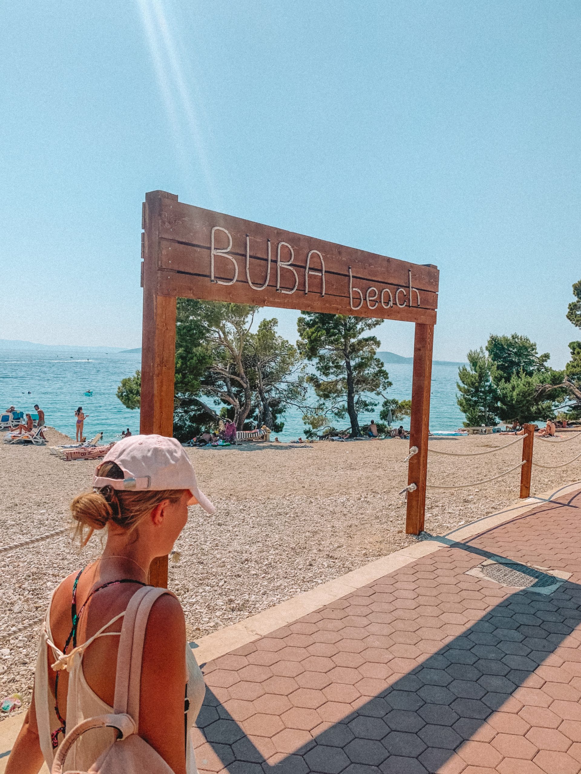 A woman walking to the beach on the promenade with the ocean in the background. How to get around in Makarska