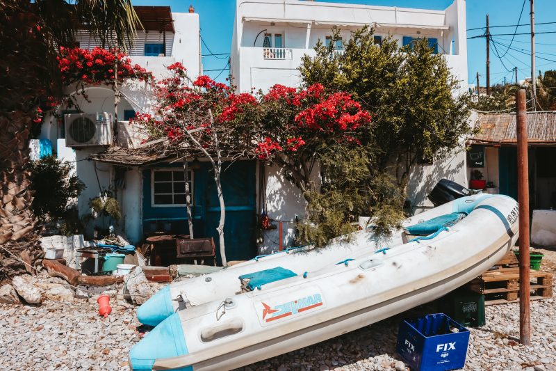 A boat on the beach with flowers blossoming around it. Where to go in Folegandros