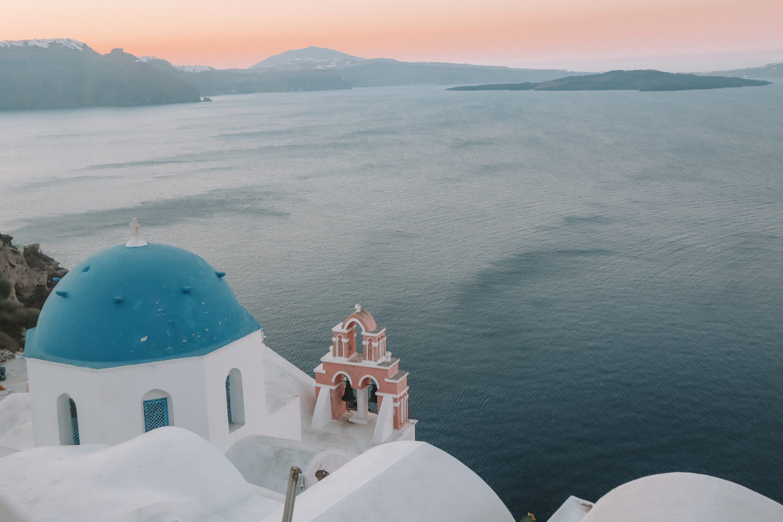 A view of the islands, blue domed church of Oia during sunrise