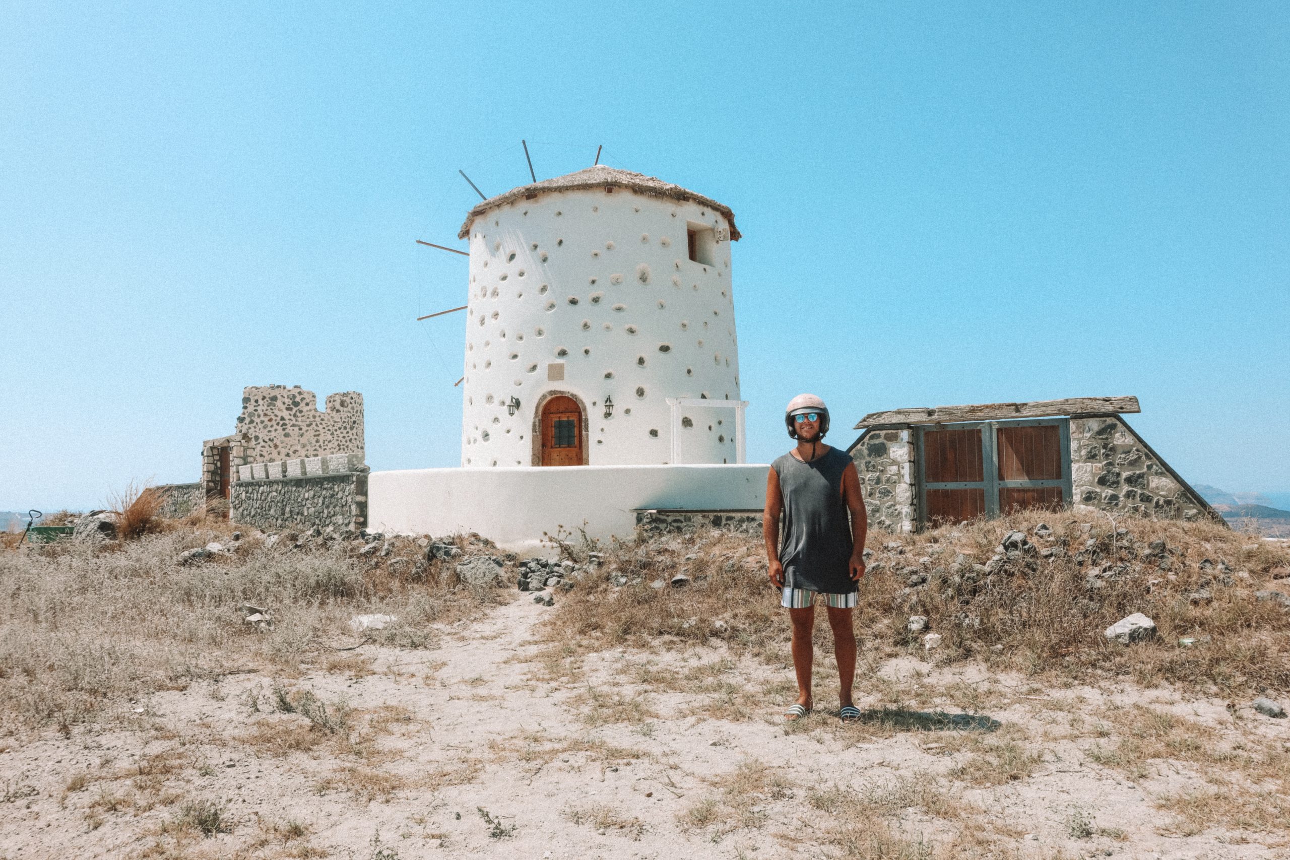 A white windmill on sparse land. What to do in Santorini