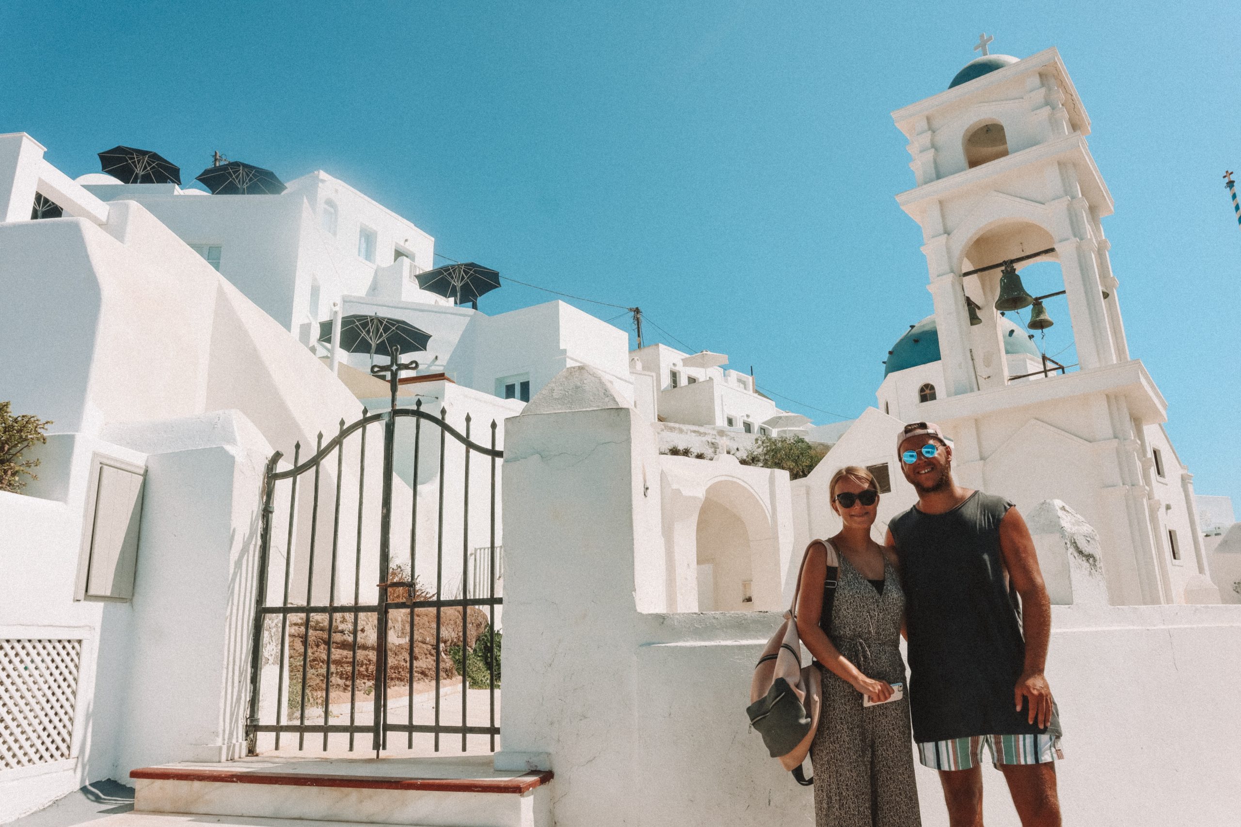 A couple in front of Imerovigli Greek church with bells