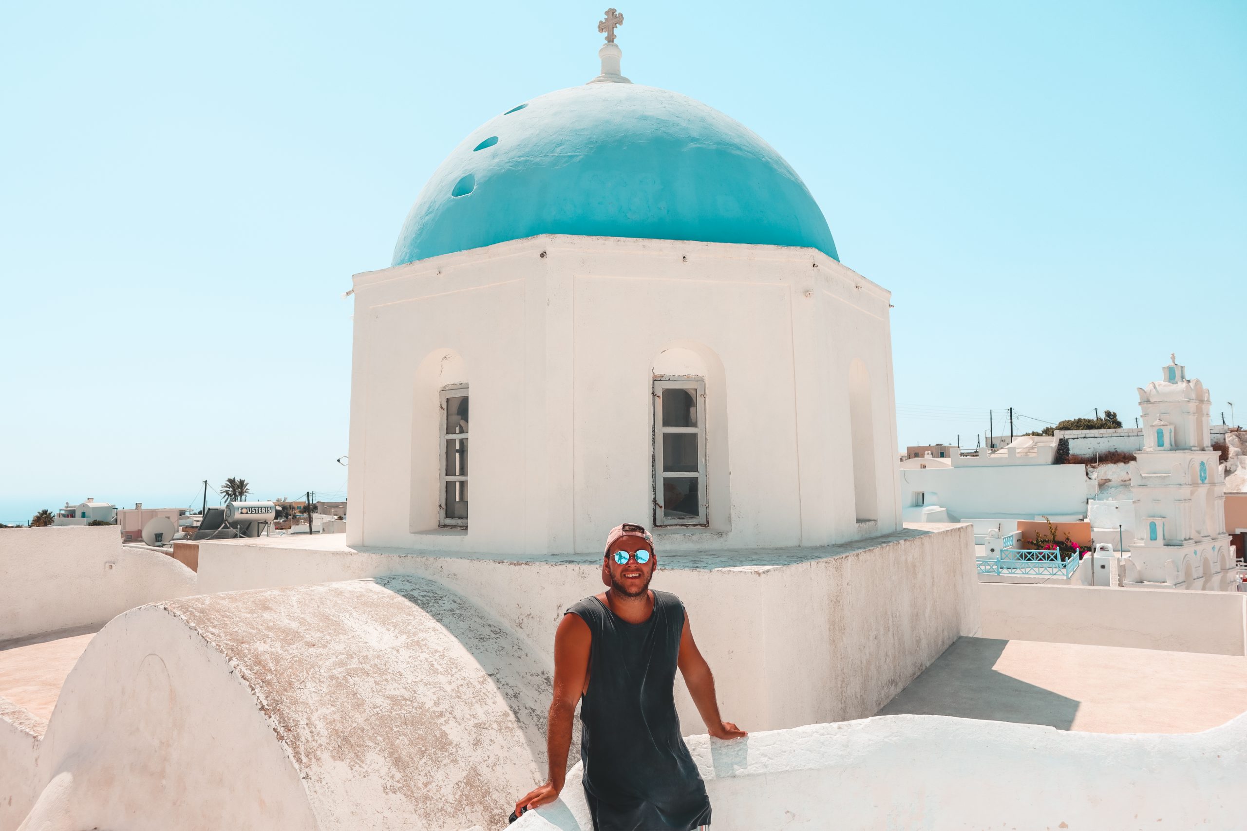 A man stood next to a blue dome church in Megalochori