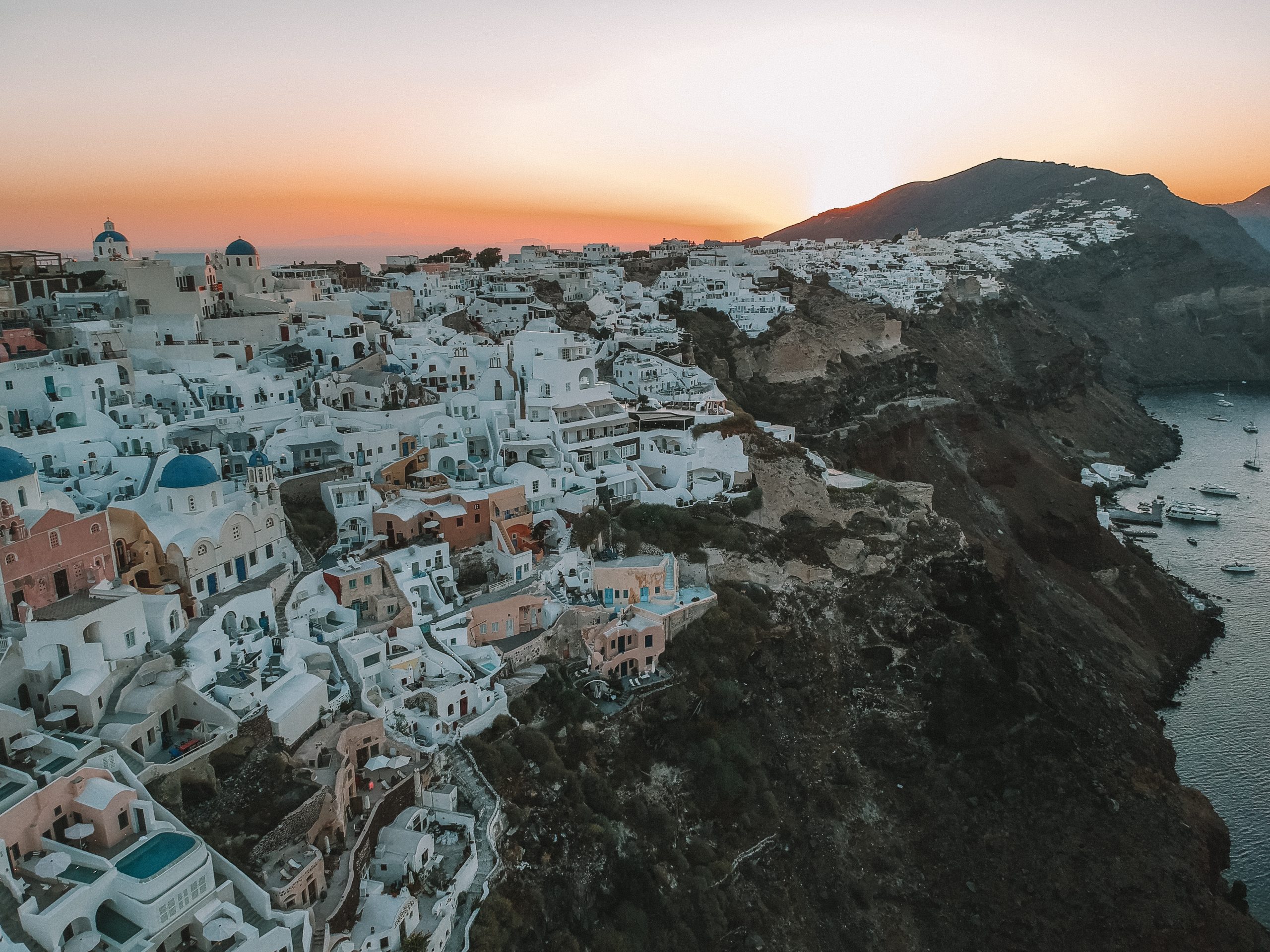 Oia cliff houses and buildings during sunrise. What to do in Santorini.