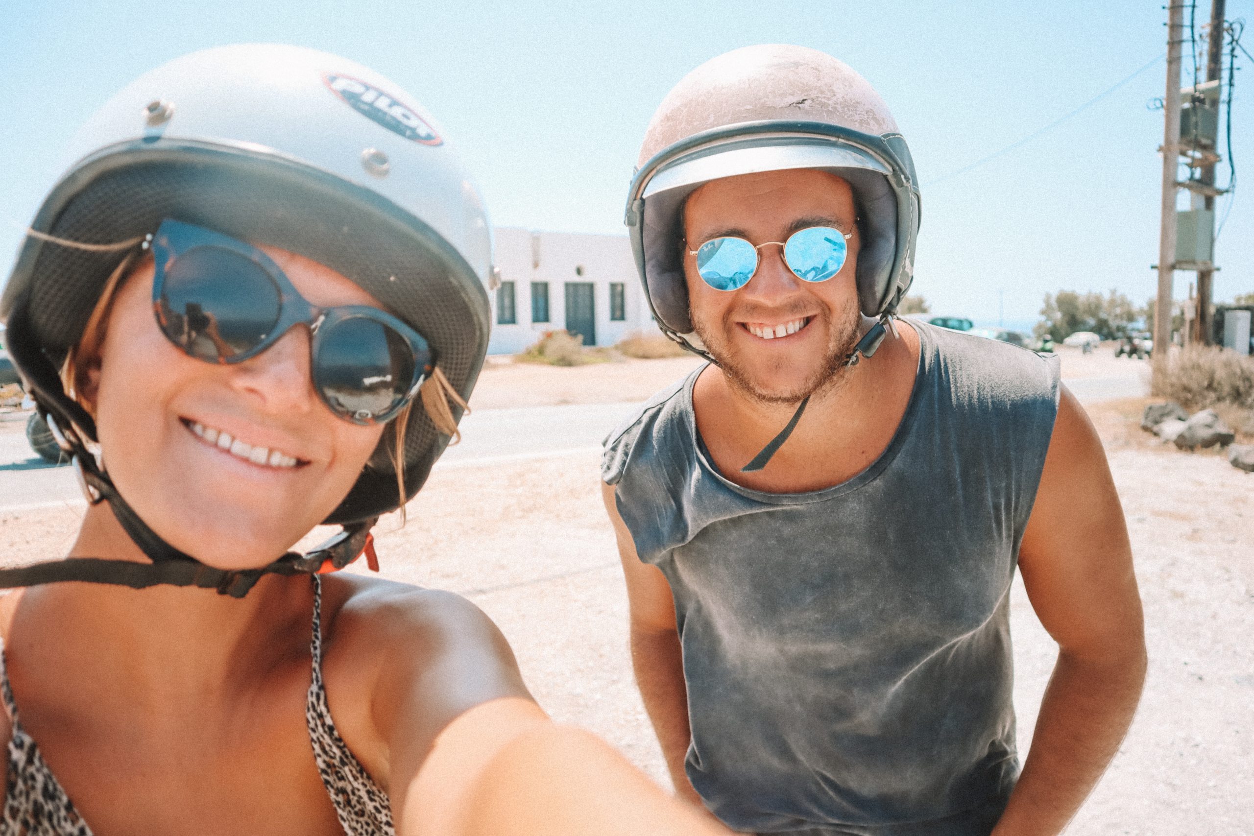 A couple taking a selfie with helmets on. How to get around in Santorini
