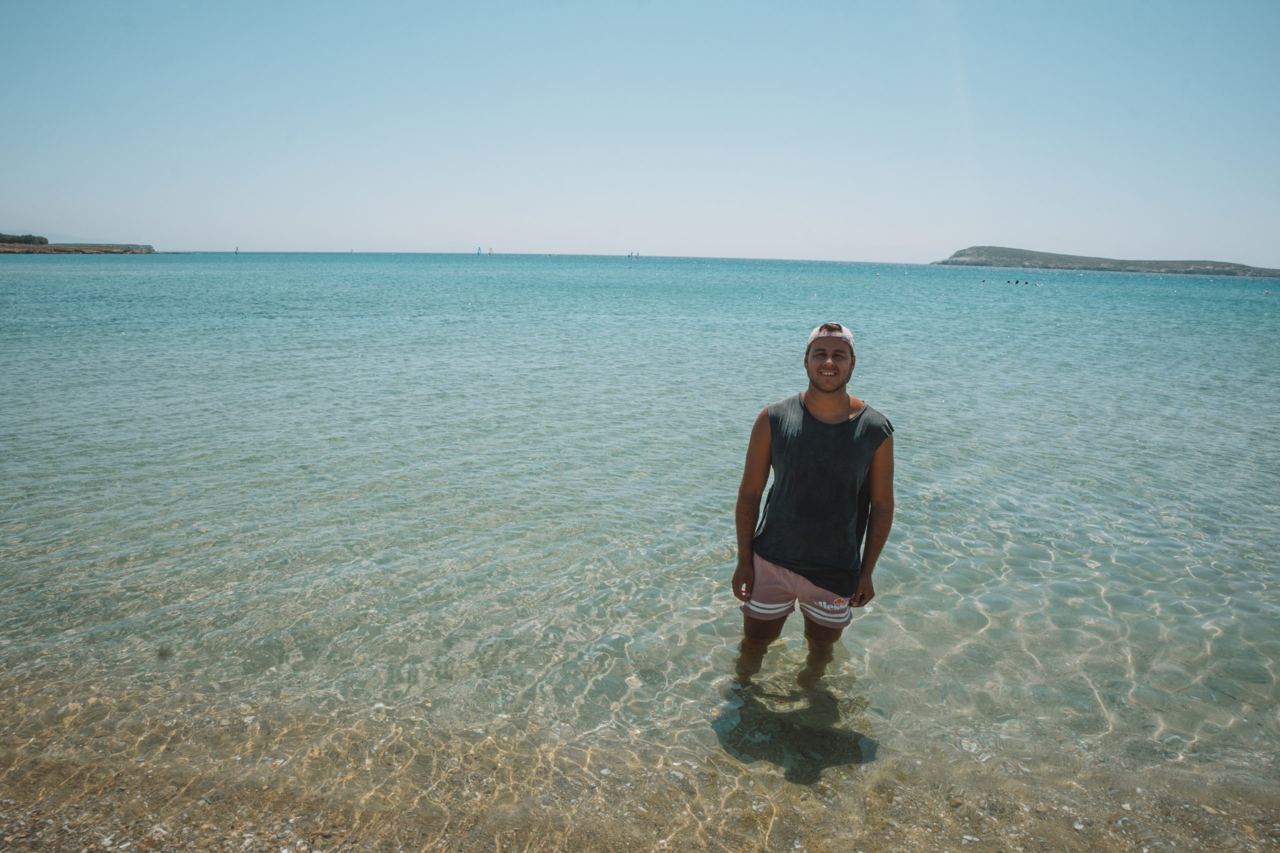 A man stood in turquoise water in Paros