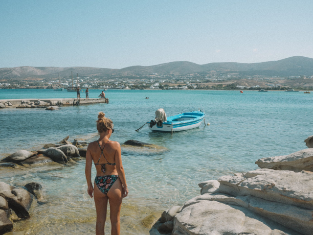 A woman stood by Kolymbithres beach and a boat