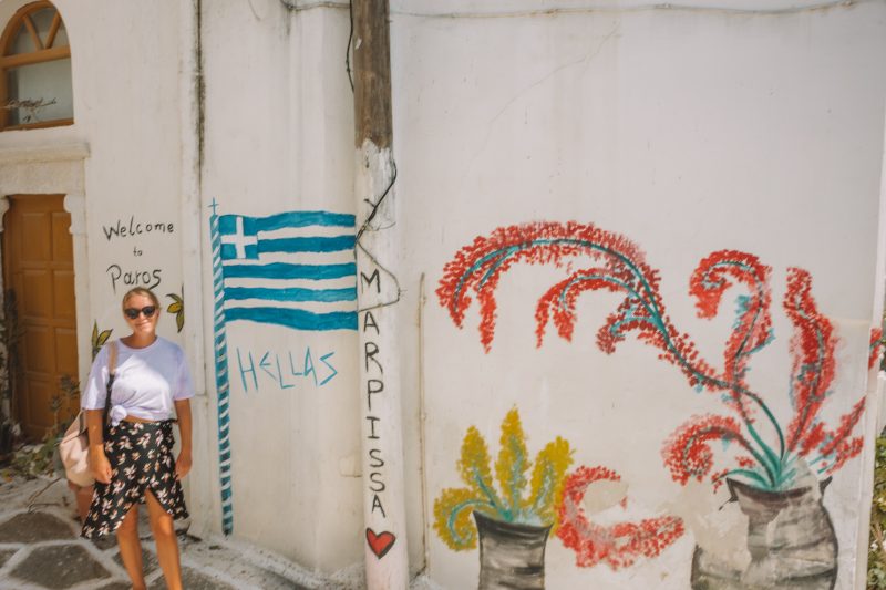 A woman stood in front of wall art in Marpissa, paros