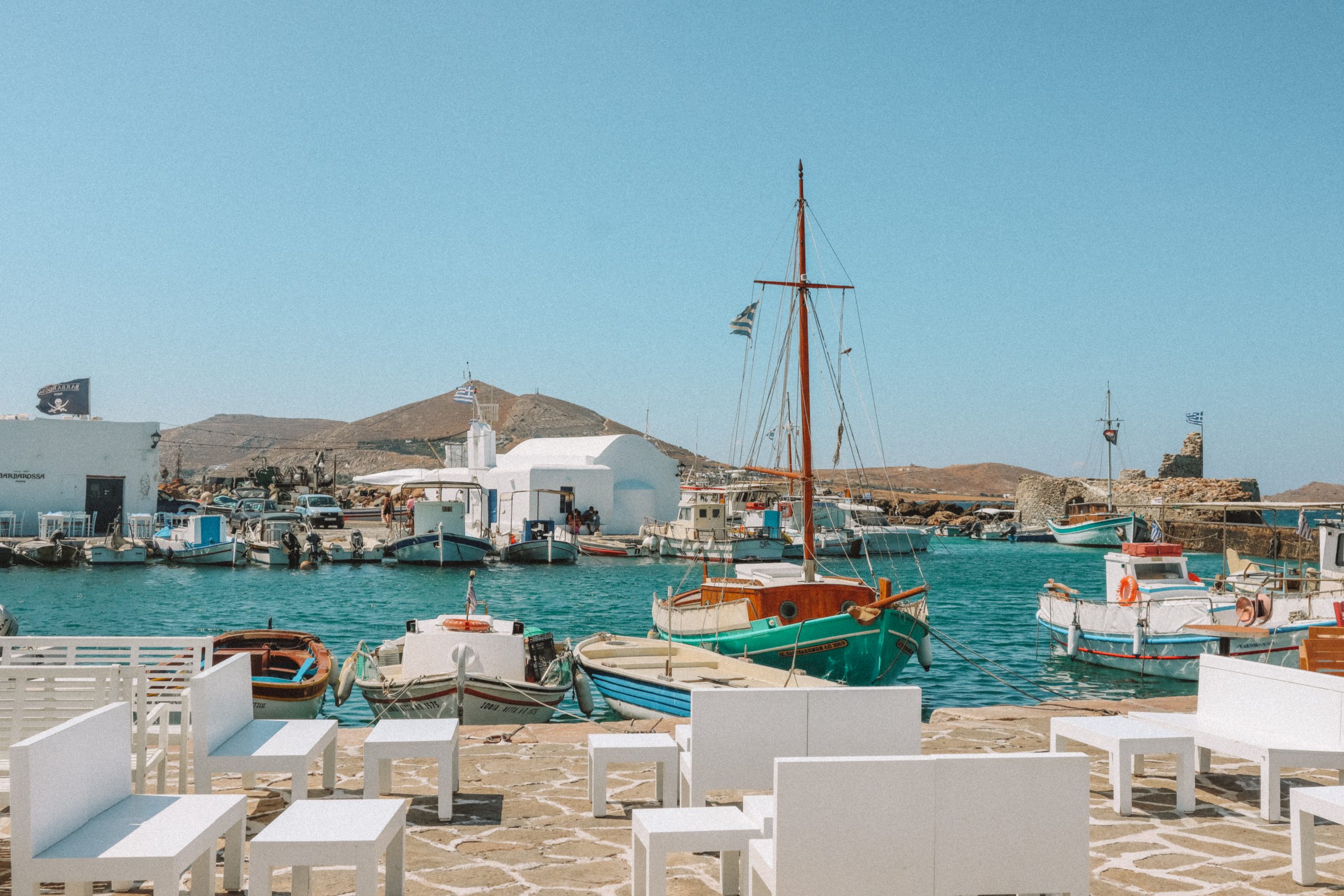 Docked boats in turquoise water at the Naoussa harbour. Things to do in Paros