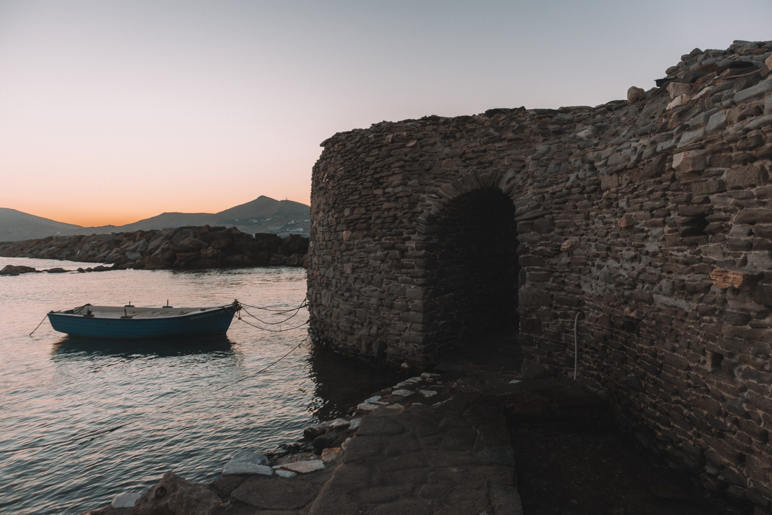 Naoussa venetian castle at sunset with a boat in the background. Paros travel blog